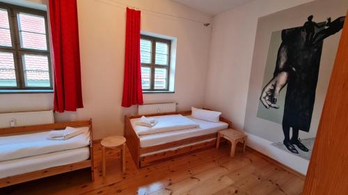 a room with two beds and a painting on the wall at Hotel Cranach-Herberge City Centre in Lutherstadt Wittenberg