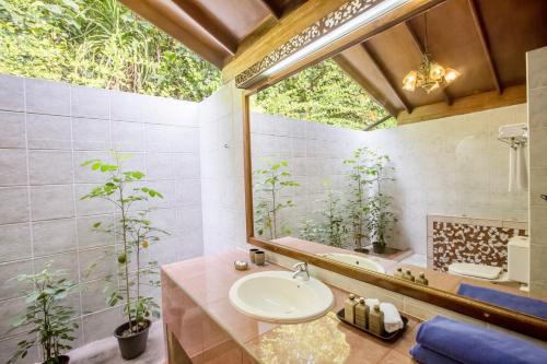 
a bathroom with a tub, sink, and plants at Reethi Beach Resort in Baa Atoll
