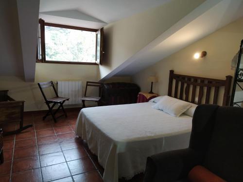 a bedroom with a bed and a couch and a window at Apartahotel Montecaoru in Arenas de Cabrales