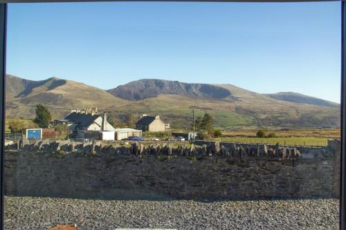 a group of birds standing on a stone wall with mountains in the background at Canolfan Y Fron in Caernarfon