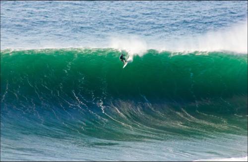 a person riding a wave on a surfboard in the ocean at BallyV House in Liscannor