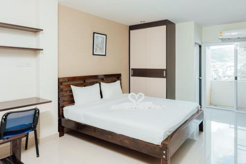 a bedroom with a bed and a desk and a window at Corner One Residence in Hat Yai
