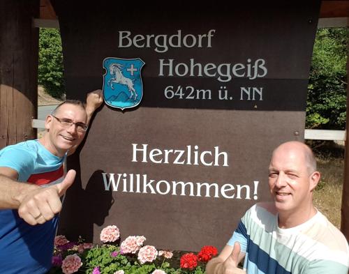two men standing in front of a sign with flowers at Hotel Silbertanne in Hohegeiß