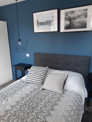 una camera da letto con pareti blu e un letto con testiera grigia di les gîtes Gillois a Gilles