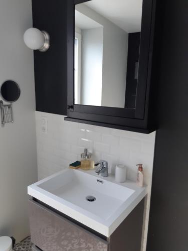 bagno con lavandino bianco e specchio di les gîtes Gillois a Gilles