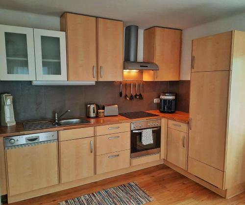 een keuken met houten kasten en een wastafel bij Apartment Fischer mit Privatstrand in Steindorf am Ossiacher See