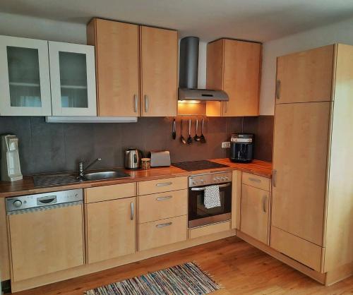 a kitchen with wooden cabinets and a sink at Apartment Fischer mit Privatstrand in Steindorf am Ossiacher See