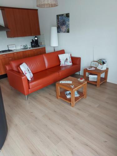 een woonkamer met een rode bank en een tafel bij De Nieuwe Stal in Scherpenisse