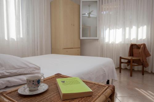 Un dormitorio con una cama con una mesa con un libro en Appartamenti Giardino al Mare, en Cavallino-Treporti