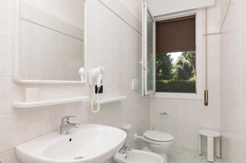 Baño blanco con lavabo y aseo en Appartamenti Giardino al Mare, en Cavallino-Treporti