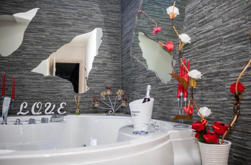 baño con bañera blanca y flores rojas en The lux, en Adrano