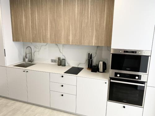 a white kitchen with a sink and a microwave at Caсtus Apartments 1 in Ivano-Frankivsk