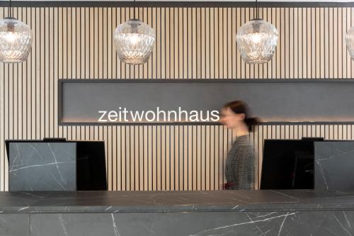 una mujer parada frente a un mostrador en una tienda en zeitwohnhaus SUITE-HOTEL & SERVICED APARTMENTS, en Erlangen