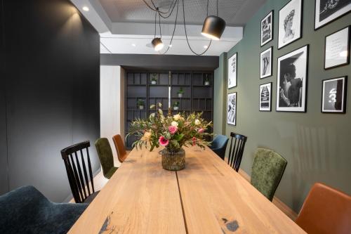 a dining room table with a vase of flowers on it at zeitwohnhaus SUITE-HOTEL & SERVICED APARTMENTS in Erlangen