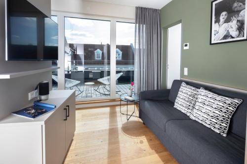 a living room with a couch and a large window at zeitwohnhaus SUITE-HOTEL & SERVICED APARTMENTS in Erlangen