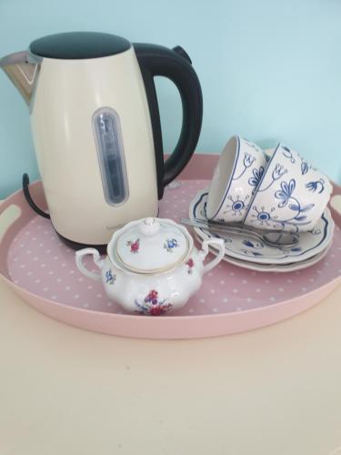 a tea set on a pink plate with a tea pot and cups at Judy's B&B private home in Cardiff