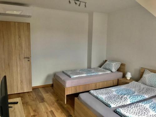 two beds in a room with wooden floors at Mátyás Vendégház 3 Rooms Apartment in Kópháza