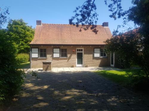 a brick house with a red roof at De Bedstee in Schoondijke