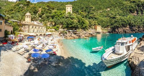 a beach with chairs and umbrellas and boats in the water at [PORTOFINO] appartamento vista mare con piscina in Rapallo