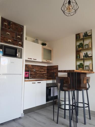 une cuisine avec des placards blancs, une table et des tabourets dans l'établissement La Rose des Sables, T2 à la mer, terrasse et garage, à Frontignan