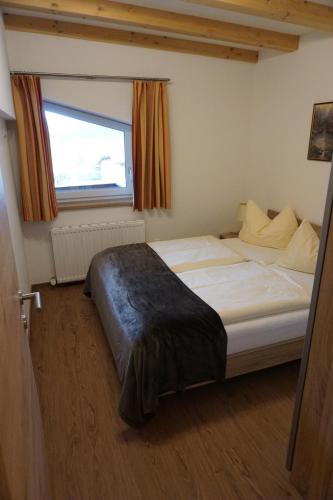 a bedroom with a large bed with a window at Appartementhaus Hüttenberger in Erpfendorf