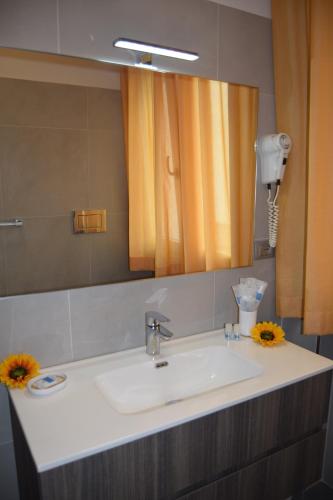 a bathroom with a sink and a mirror and flowers at Orchidea Marina in Tirrenia