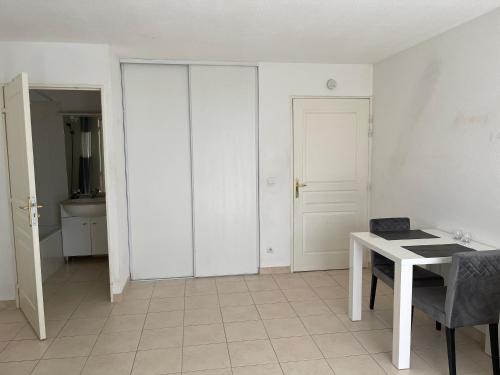 Cette chambre blanche dispose d'une table et d'une porte. dans l'établissement Les Bastides de Gauguin, à Saint-Laurent-du-Var