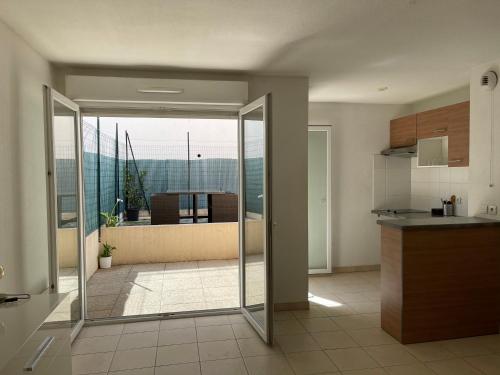 une cuisine avec une porte en verre menant à un balcon dans l'établissement Les Bastides de Gauguin, à Saint-Laurent-du-Var