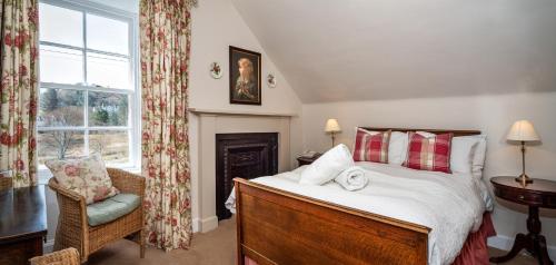 a bedroom with a bed and a chair and a window at Hotel Eilean Iarmain in Isleornsay