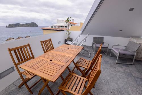 ein Holztisch und Stühle auf einem Balkon in der Unterkunft CASA DAS TAIPAS in Vila Franca do Campo