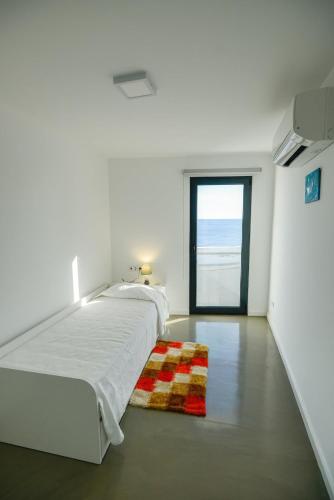 a white bedroom with a large bed and a window at CASA DAS TAIPAS in Vila Franca do Campo