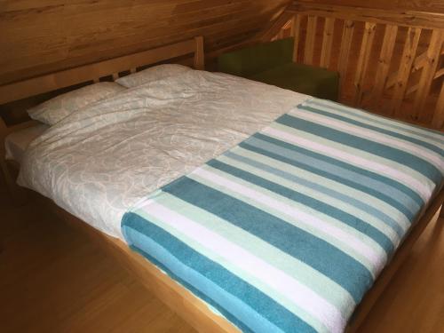 a bed with a blue and white striped blanket on it at Melluzi chalet in Jūrmala