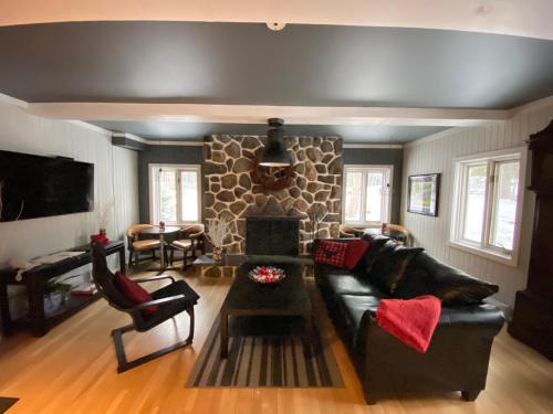 sala de estar con sofá negro y chimenea de piedra en Hôtel Far Hills, en Val-Morin