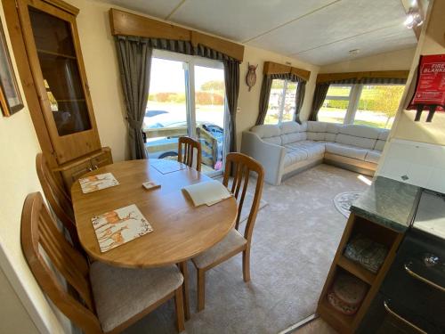 a dining room with a table and chairs and a couch at Happydays Caravan hire Whithorn 1 in Bailliewhir