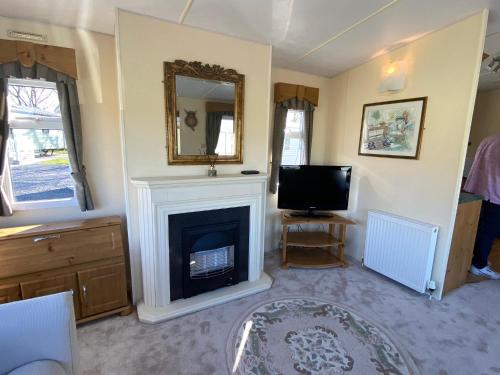 a living room with a fireplace and a television at Happydays Caravan hire Whithorn 1 in Bailliewhir