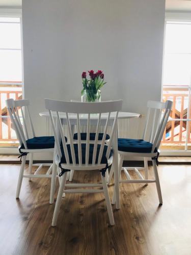 una mesa con tres sillas y un jarrón de flores. en Apartament Marina Mazury, en Węgorzewo