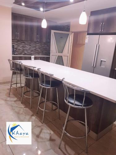 a kitchen with a large white counter and stools at Khaya B&B in Cape Town