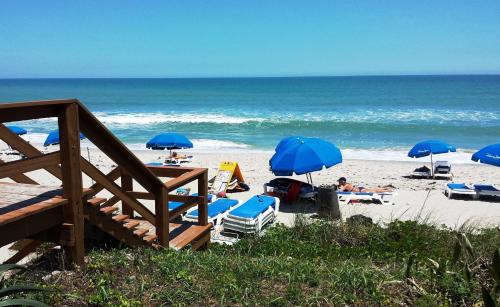 a group of people laying on the beach under umbrellas at Radisson Suite Hotel Oceanfront in Melbourne