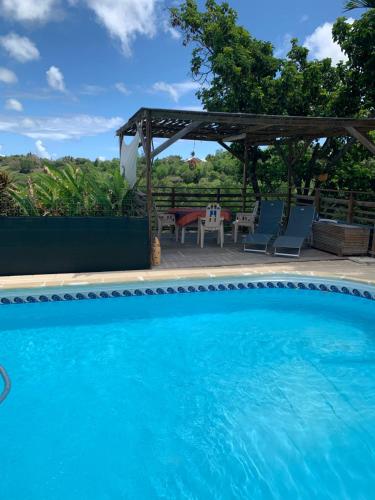 a swimming pool with a gazebo and a table and chairs at La citronnelle in Sainte-Anne