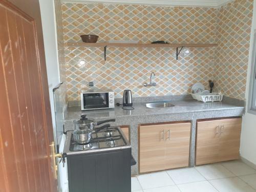 a small kitchen with a stove and a microwave at Residence Delaure in Bingerville