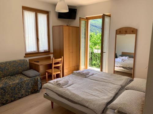 a bedroom with a bed and a chair and a mirror at Hotel Garnì Delle Rose in Dro