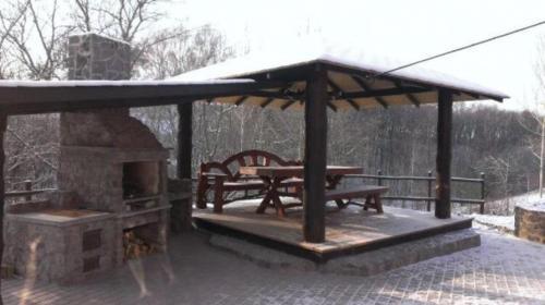 a pavilion with a picnic table and a stone oven at Дом для отдыха в лесу in Berëzovka