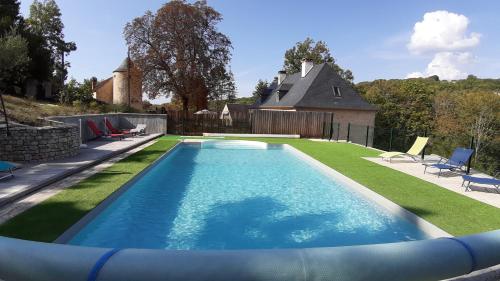 a swimming pool with a lawn and a house at Domaine de Galoubet Lot in Beaumat