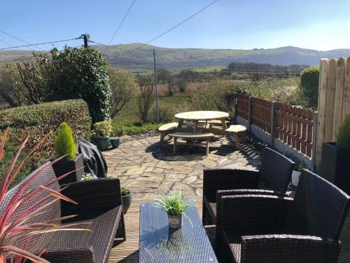 a patio with a table and chairs and a picnic table at The Little Boat House in Talsarnau