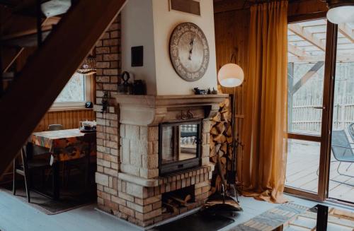 uma sala de estar com uma lareira de tijolos e uma mesa em Dom w Puszczy em Supraśl