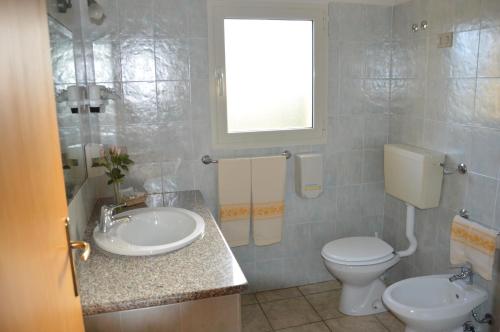 a bathroom with a sink and a toilet and a window at Hotel La Palma in San Teodoro
