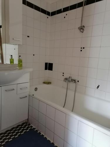 a white bathroom with a tub and a sink at Rita's FeWo in Grossschönau