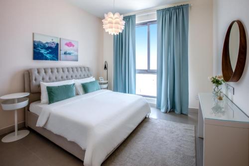 a white bedroom with a large bed and a window at A Luxury Aprt 2 bedrooms Balcony with wonderful view Mall access hi speed WIFI Beach access & much more for Family Only in Rayyā