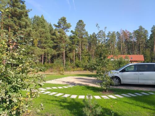 a car parked in a yard next to a forest at Mazury domek całoroczny Pelnik gm Ostróda jezioro las in Pelnik
