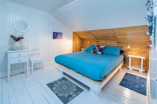 1 dormitorio con cama azul y escritorio en L'OASIS DU MASSIF - Spa, BBQ, foyer et plaisir !, en Saint-Paul-de-Montminy
